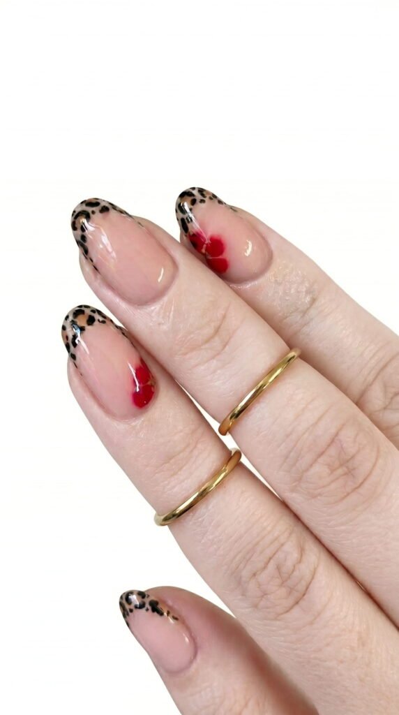 Almond nude nails with leopard print tips and small red heart accent