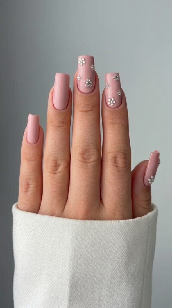 Long square pink nails with 3D flower charms and rhinestone accents